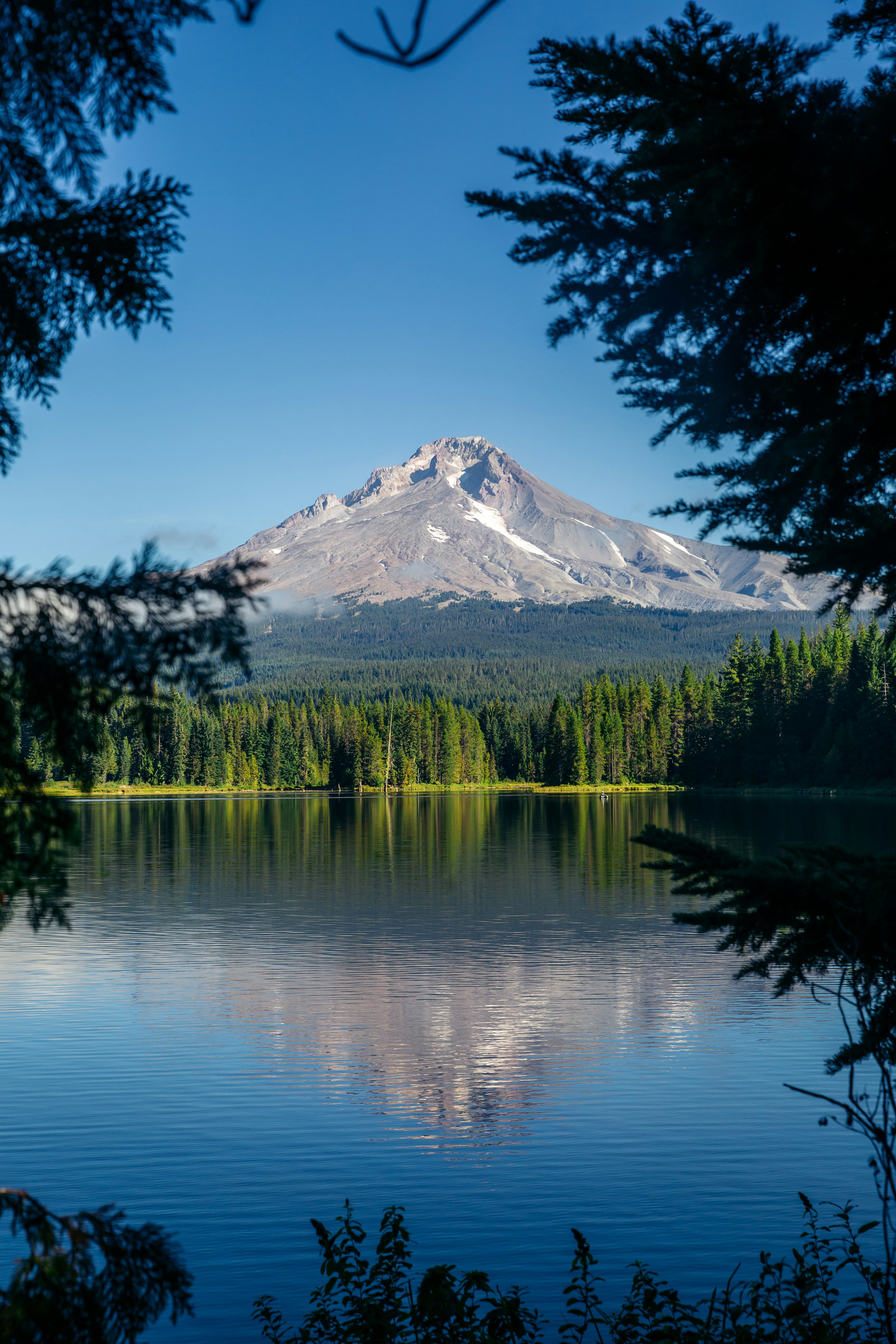 A majestic mountain peak reflected in a clear, still lake, surrounded by green forest