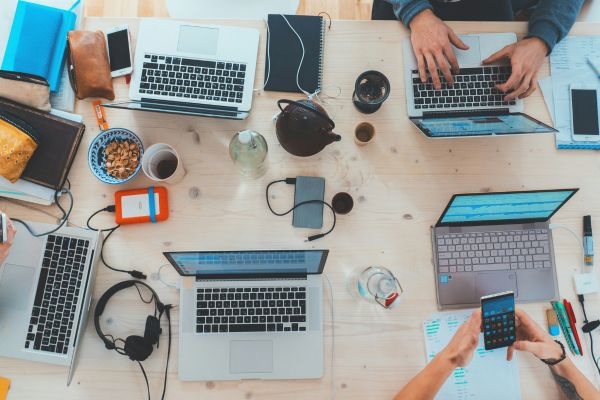 Candid view of a busy, crowded work area with multiple laptops and a sense of active work
